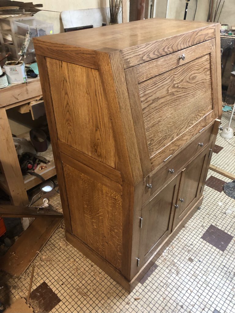 Mobilier en bois en cours de restauration dans un atelier d'ébénisterie, avec des détails soignés et une finition en chêne.