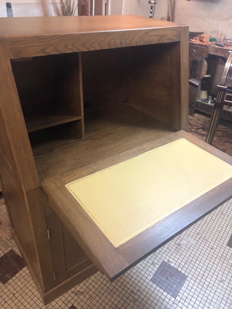 Établi en bois avec un plateau dépliable en cuir, destiné à la rédaction ou au travail de bureau.