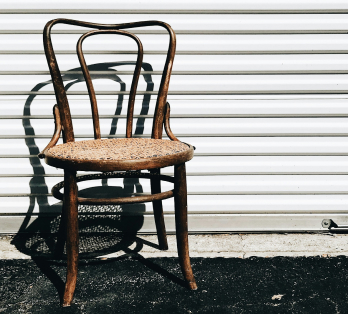 Chaise en bois vintage, ancienne et en paille, contre un mur en métal.